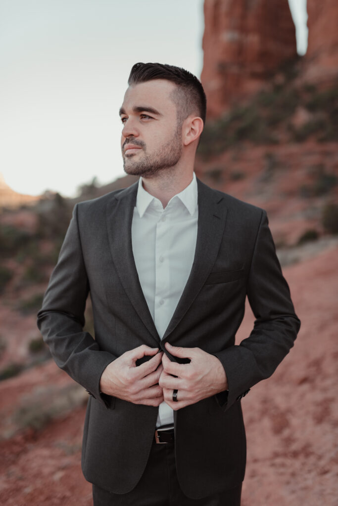 Groom in a beige linen suit with Sedona red rocks in the background.