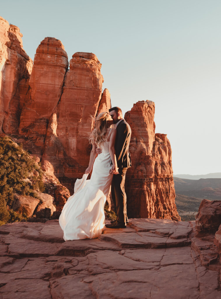 Couple holding hands with a dramatic Sedona sunset behind them.