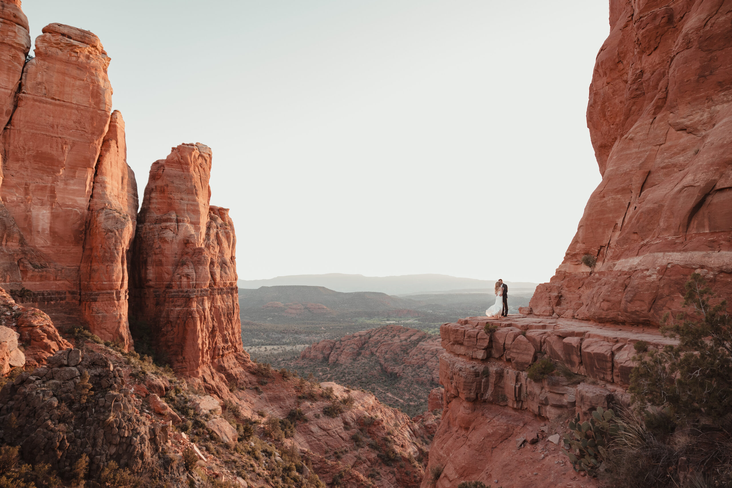 Couple holding hands with a dramatic Sedona sunset behind them.