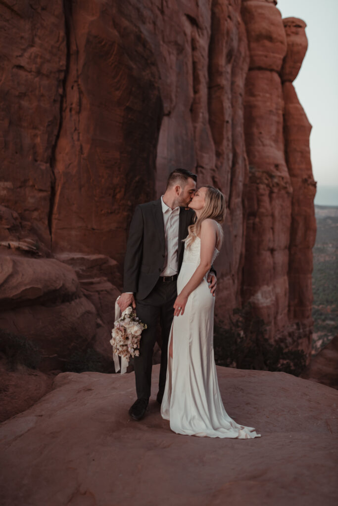 Couple holding hands with a dramatic Sedona sunset behind them.