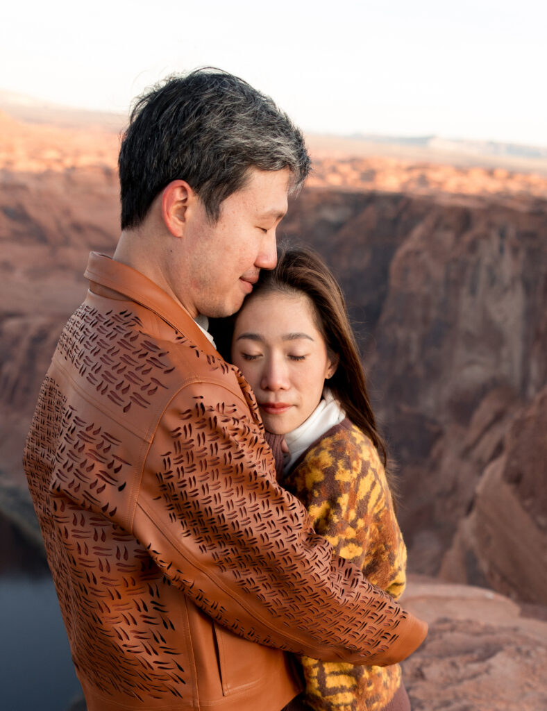 Wind in their hair and desert light all around, the couple stands silhouetted at the overlook, holding each other tightly against the vast Arizona sky.