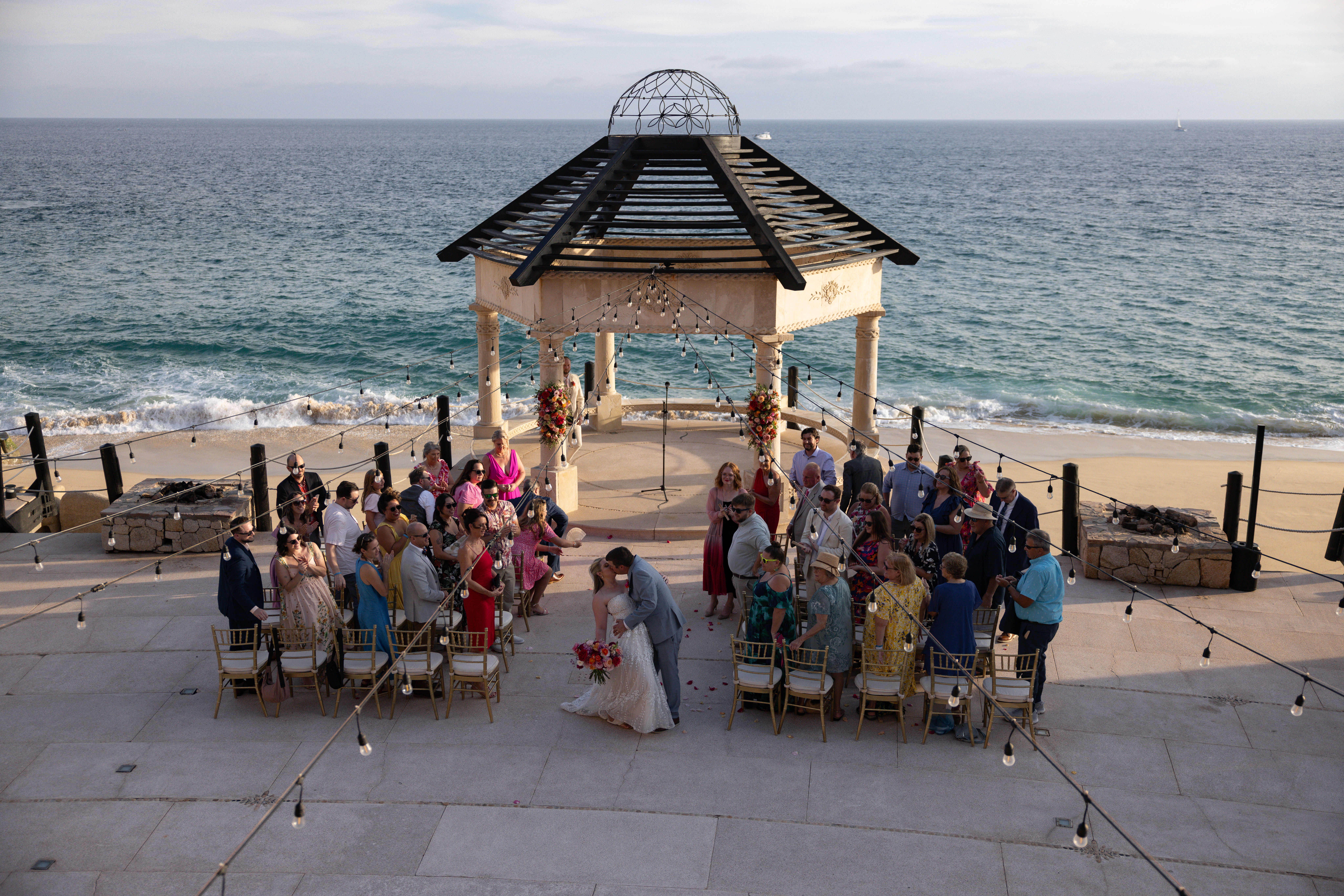 Grand Solmar Cabo San Lucas oceanfront wedding ceremony with bride, groom, and guests gathered under the stone gazebo overlooking the Pacific, photographed by Arizona destination wedding photographers.